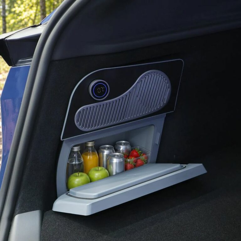 Glacière électrique intégrée au rangement du coffre d’une Tesla Model Y, porte ouverte, garnie de boissons et de fruits