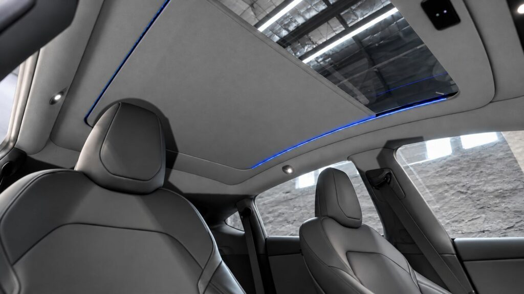 Pare-soleil électrique déployé sous le toit panoramique d’une Tesla Model Y, sièges gris